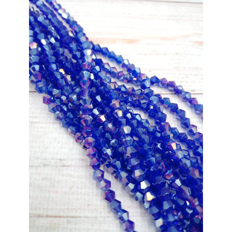 Біконус, розмір 4*4 мм. Синій прозорий з райдужним покриттям Біконус, розмір 4*4 мм. Синій прозорий з райдужним покриттям